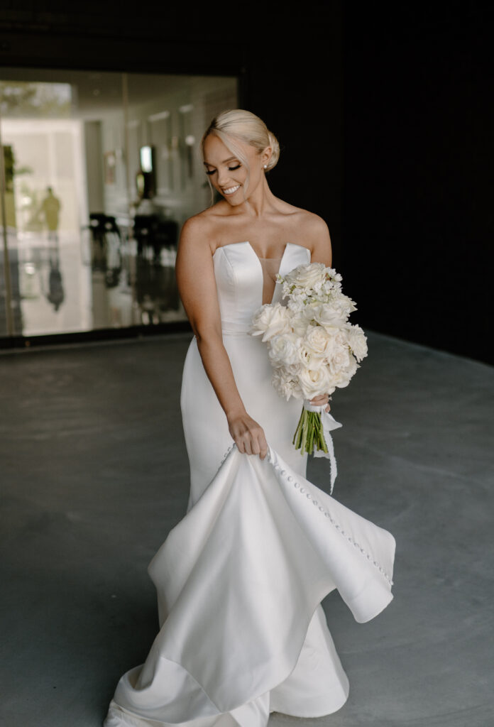 A bride posing with her bouquet made of all white long stemmed roses
