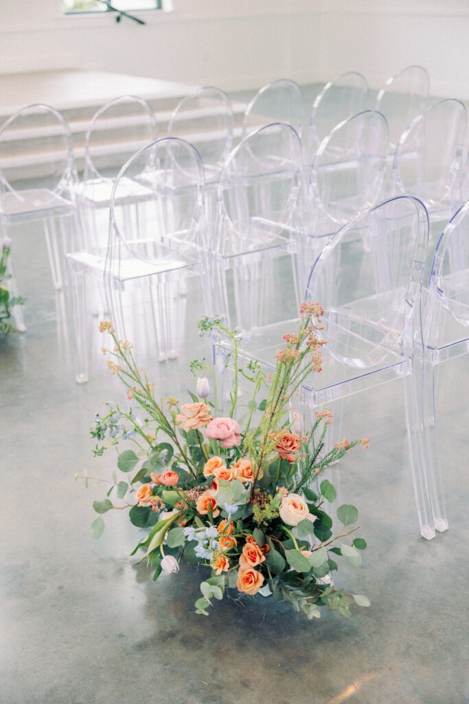 A colorful ground floral arrangement used as an aisle marker for spring wedding ceremony 