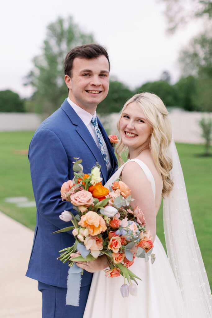 Bride and groom posing with the brides colorful spring bridal bouquet 
