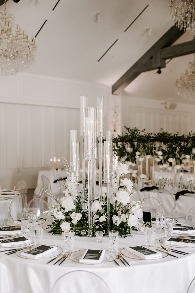 A crystal candelabra with lush white florals and greenery surrounding it at guest tables.