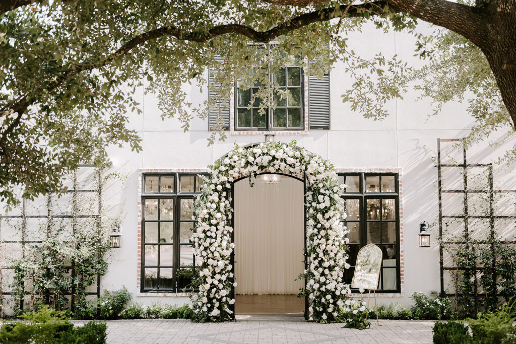 Lush floral arch surrounding a venue door for a wedding entrance