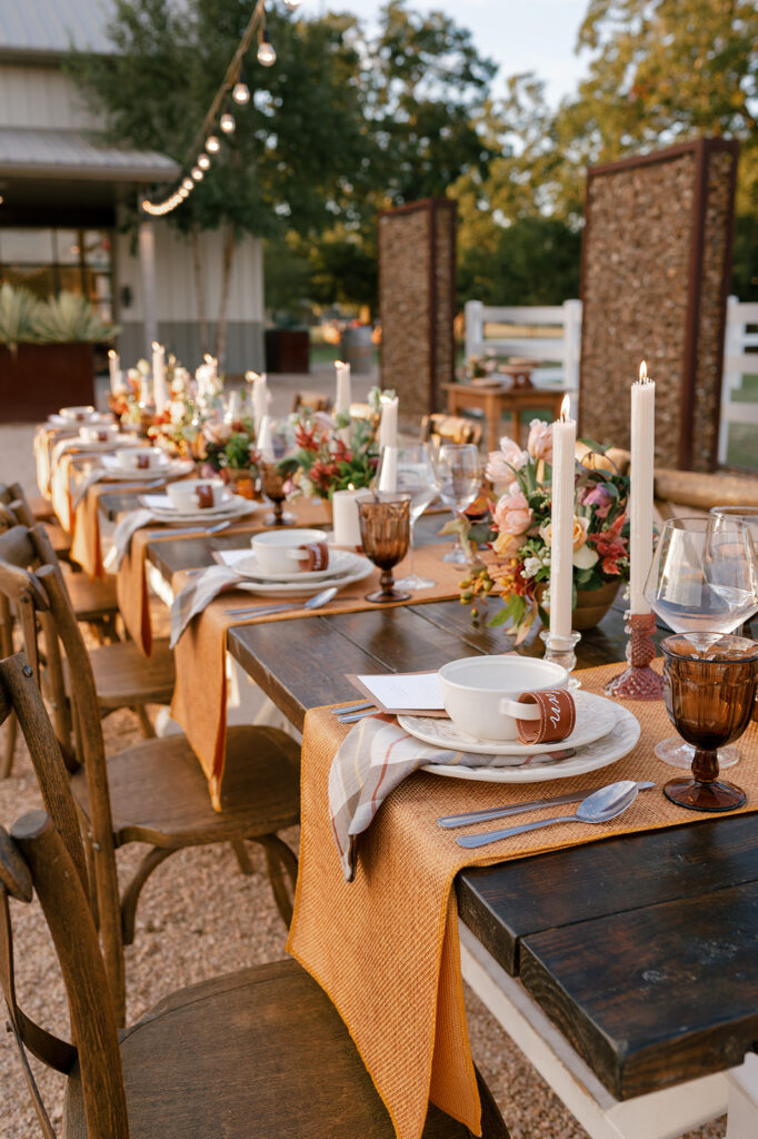 A fall inspired wedding tablescape with florals and decorative accents in hues of golden yellow, white, and burgundy 