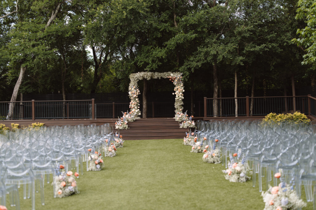 Modern floral arch made of baby's breath and pastel colored flowers with matching ground floral aisle markers for wedding ceremony
