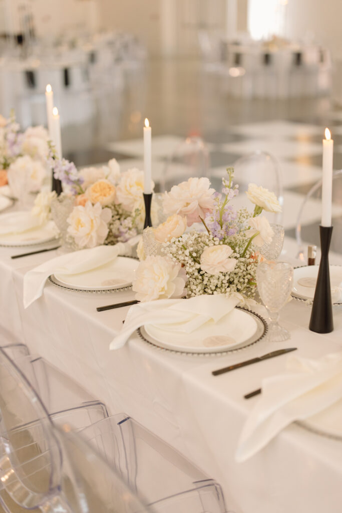 Modern wedding centerpieces with floral arrangements made with baby's breath and colorful pastel flowers mixed with taper candles with black holders