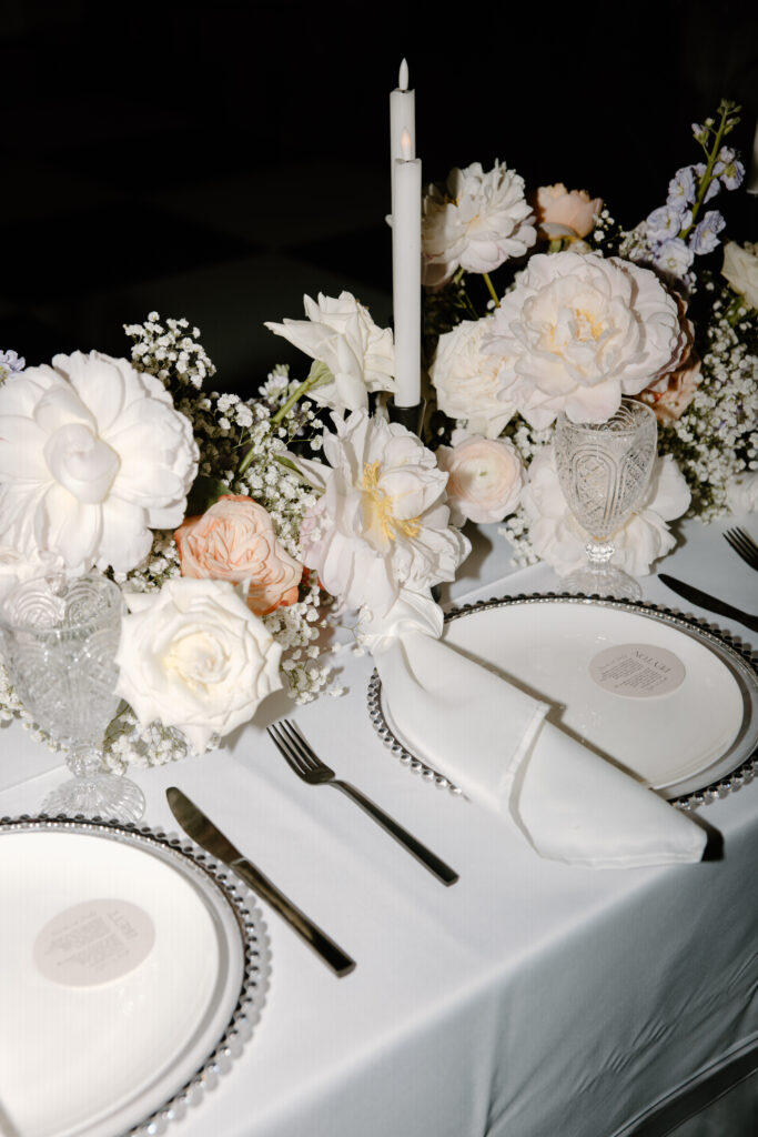 Modern wedding centerpieces with floral arrangements made with baby's breath and pastel colored flowers mix with taper candles with black holders