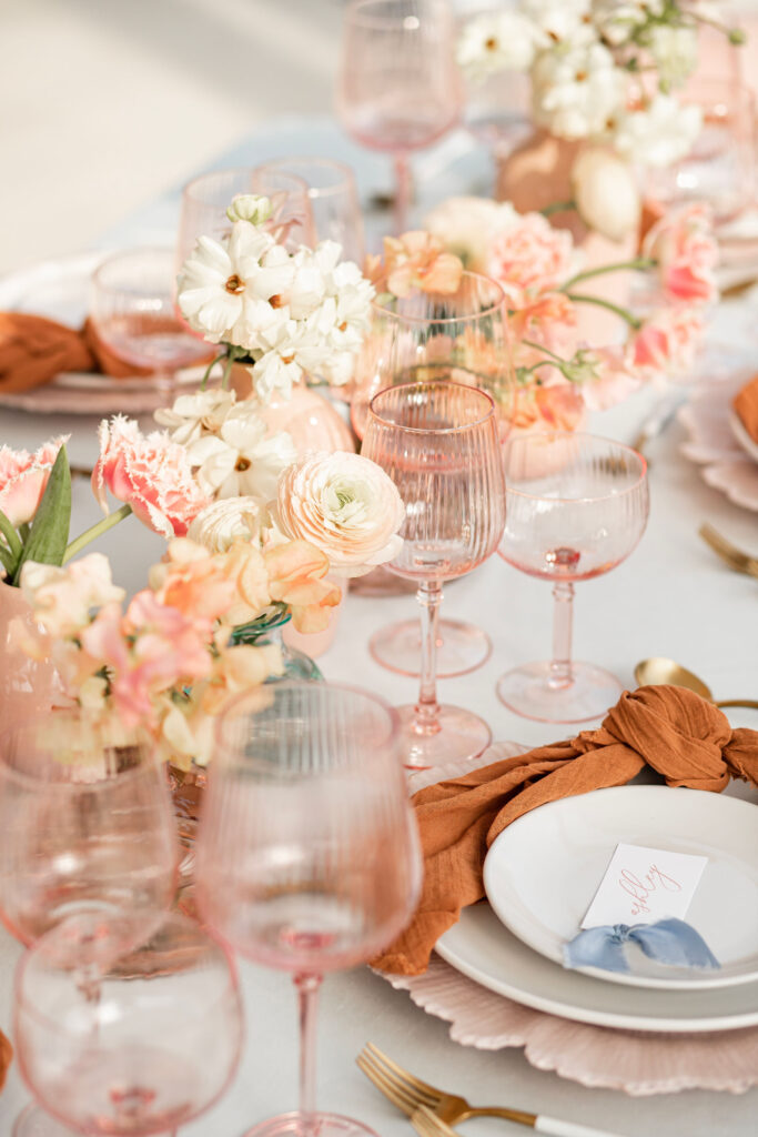 Pink bud vases filled with fringed pink tulips, blush butterfly ranunculus, and peach toned ranunculus