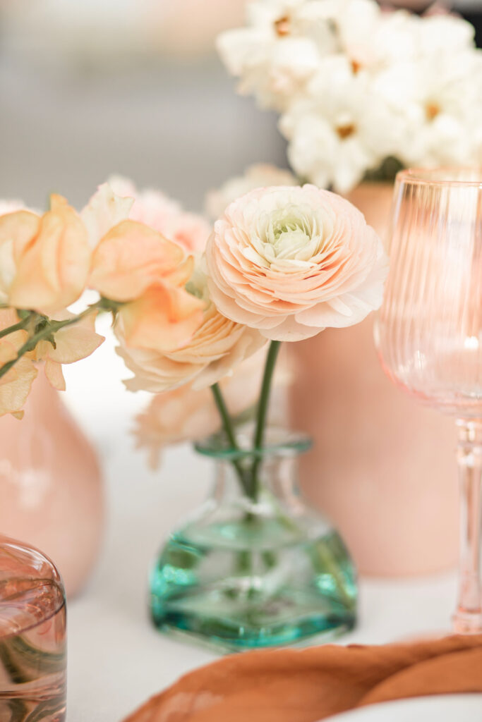 Pink bud vases filled with fringed pink tulips, blush butterfly ranunculus, and peach toned ranunculus
