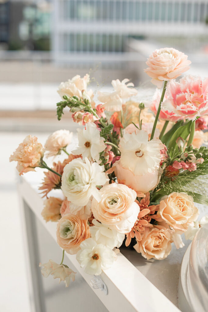 An elegant floral arrangement with blush, pink, and peach florals including ranunculus and tulips