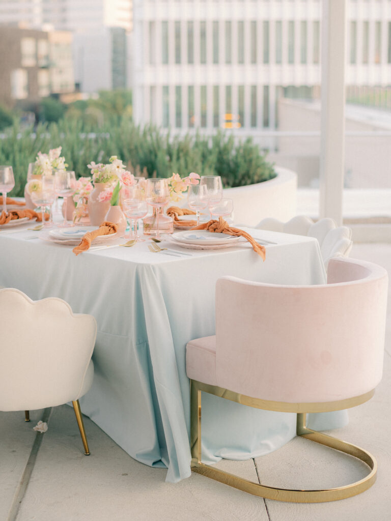 An elegant bridal brunch for the bride and her bridesmaids with dainty pastel colored flowers, pink glassware, and blue linens