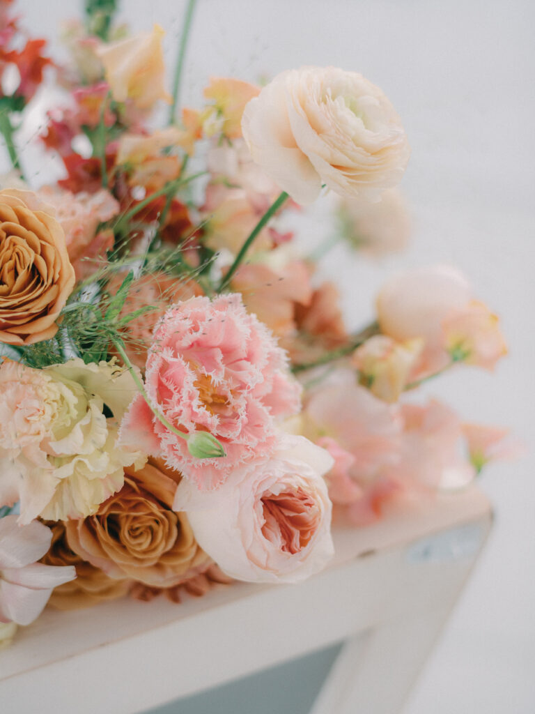 An elegant floral arrangement with blush, pink, and peach florals including ranunculus, roses, and tulips
