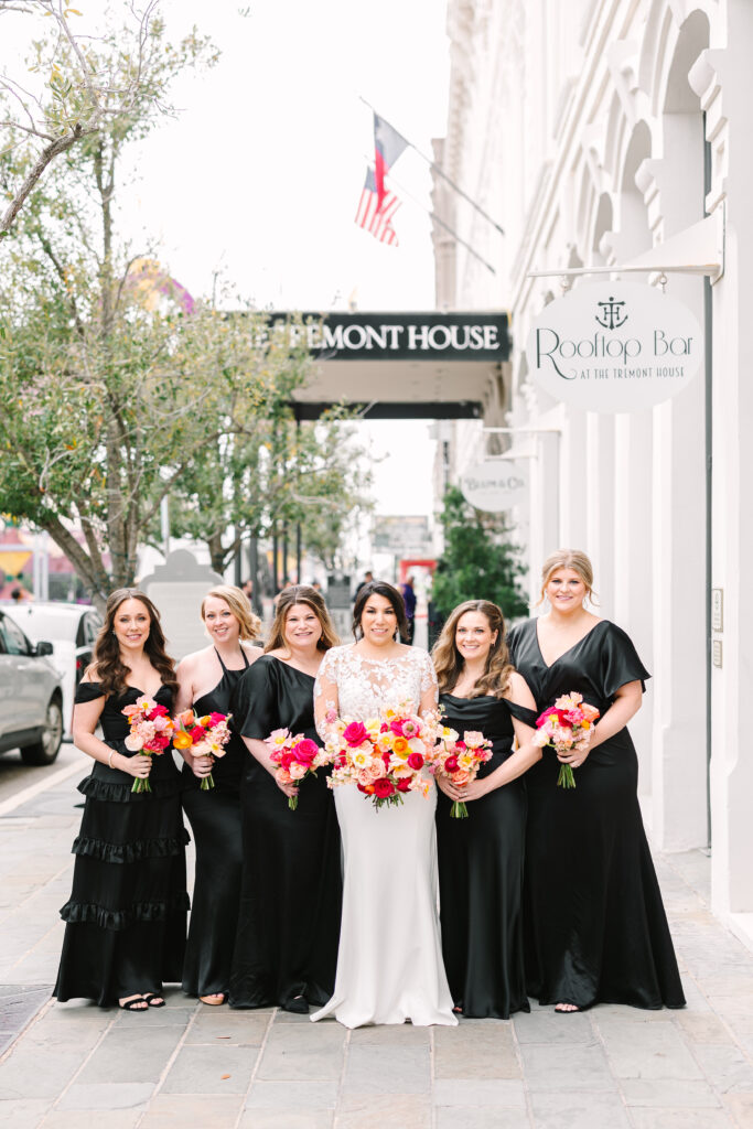 Bride and her bridesmaids posing with their colorful bouquets made with pink and orange flowers