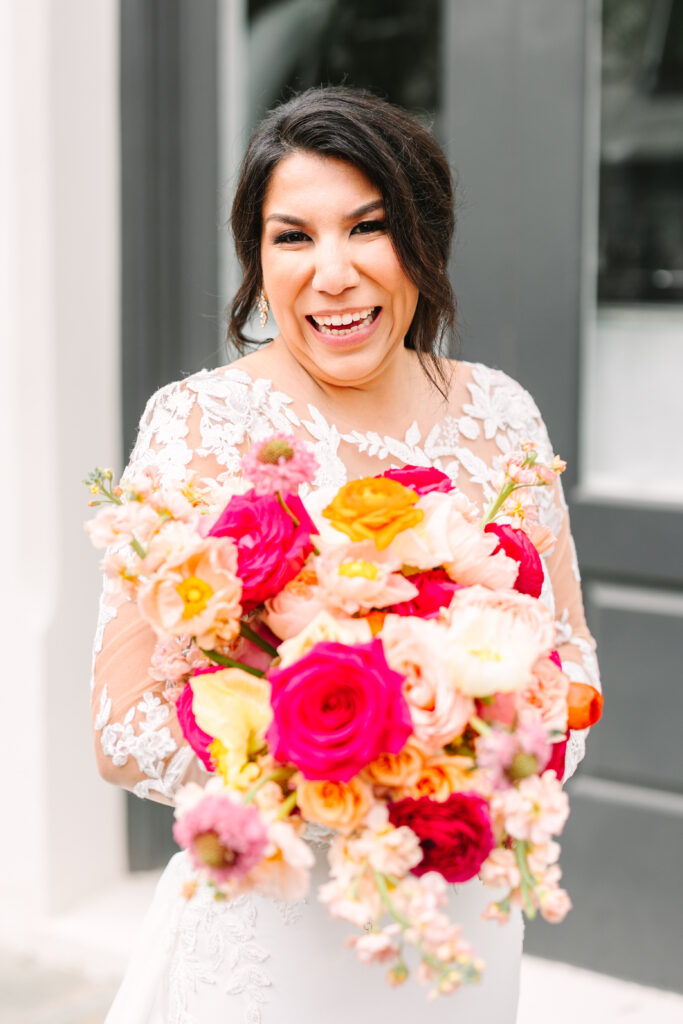 Bride posing with her colorful bridal bouquet made with pink and orange flowers