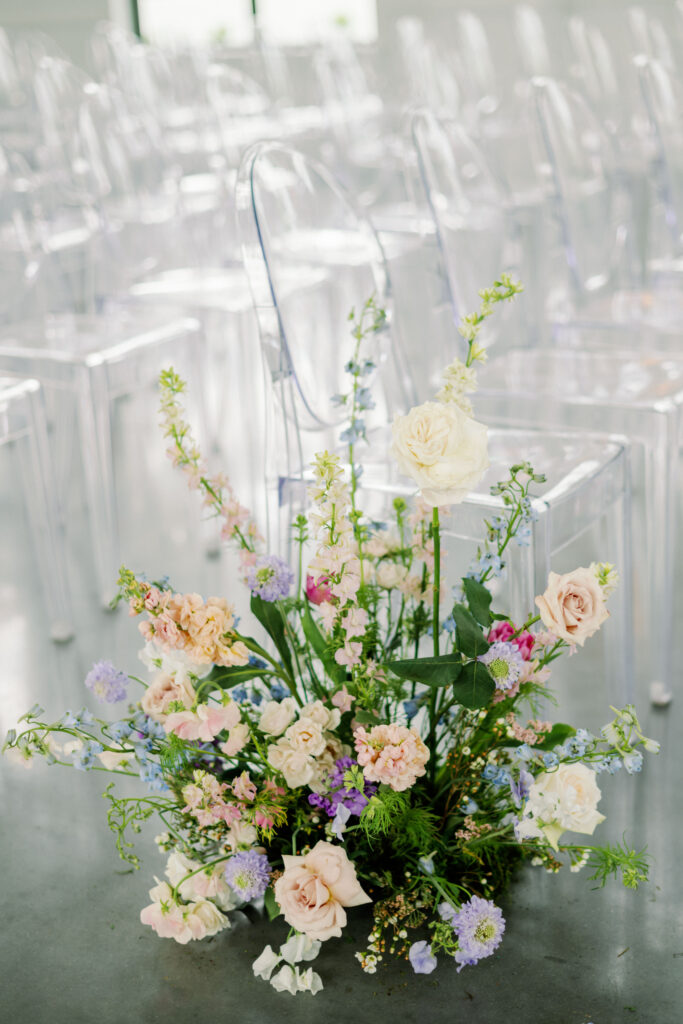 Textural pastel floral arrangement placed on the ground going down the aisle for wedding ceremony