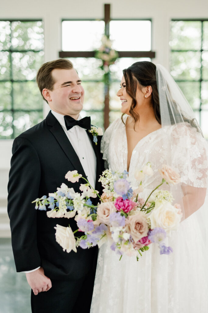 Bride and groom posing with her whimsical pastel colored bridal bouquet and matching boutonniere or spring wedding