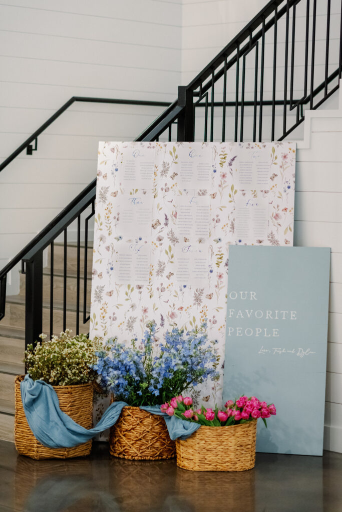 Whicker baskets with colorful blooms placed on the ground in front of wedding sign